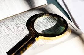 A magnifying glass lays atop a dictionary page open to the word "Malpractice."