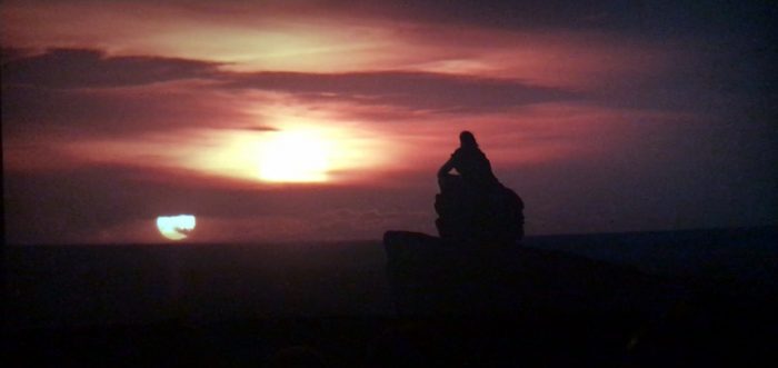 A Shadowed Luke Skywalker looking off at a binary sunset in Star Wars: The Last Jedi.