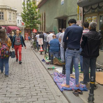 Muslims praying in the streets of Istanbul, Turkey. It's a modern urban scene.