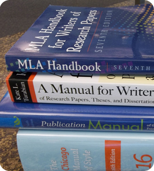 A stack of the MLA Handbook, the Turabian Manual for Writers, the APA Style Guide, and the Chicago Manual of Style